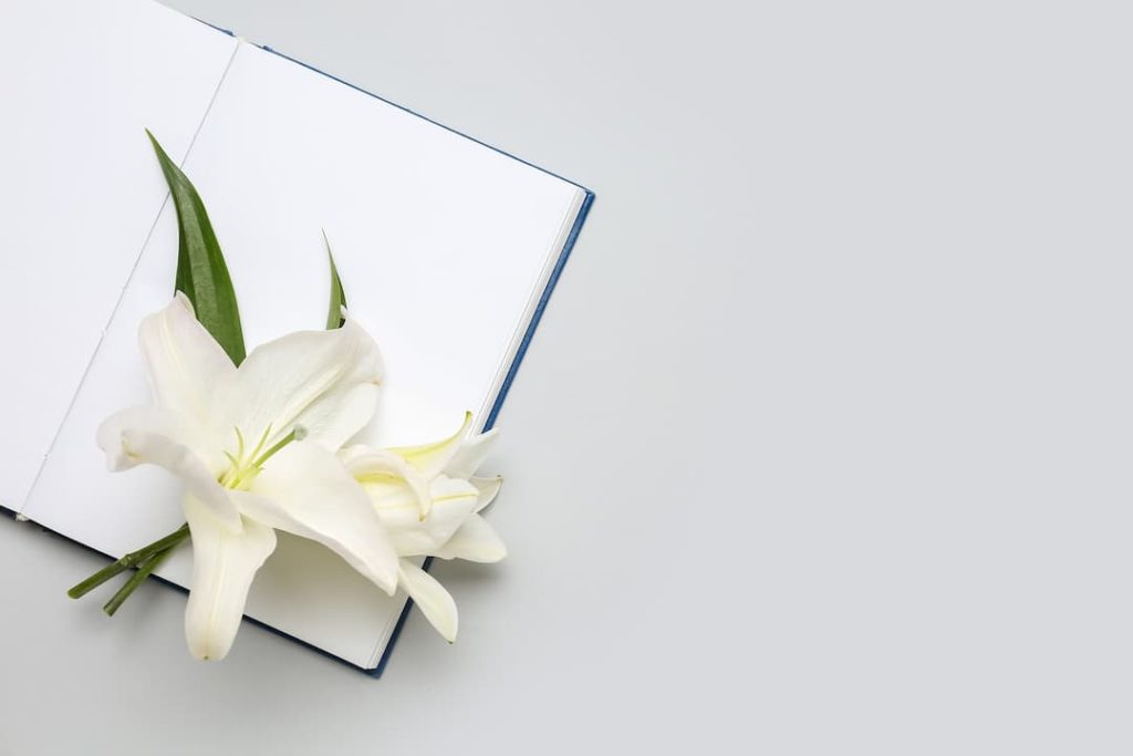 Open memory book with white lily for funeral service